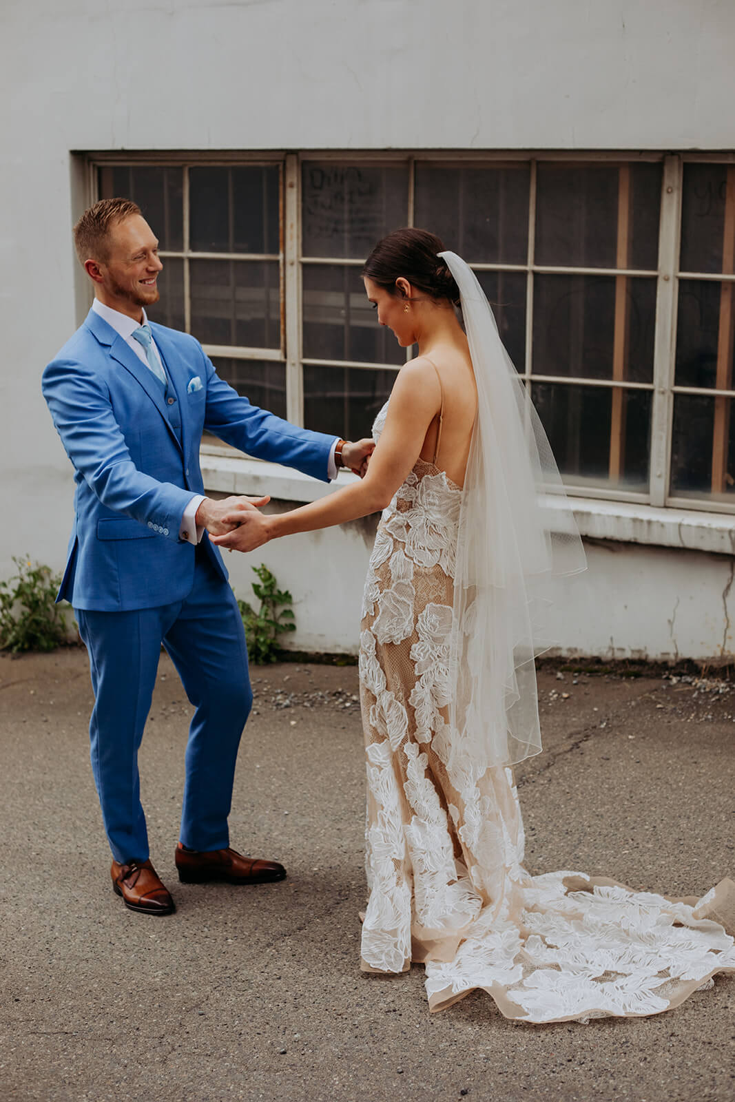 Bride and groom hold hands after first look at industrial wedding venue in Seattle