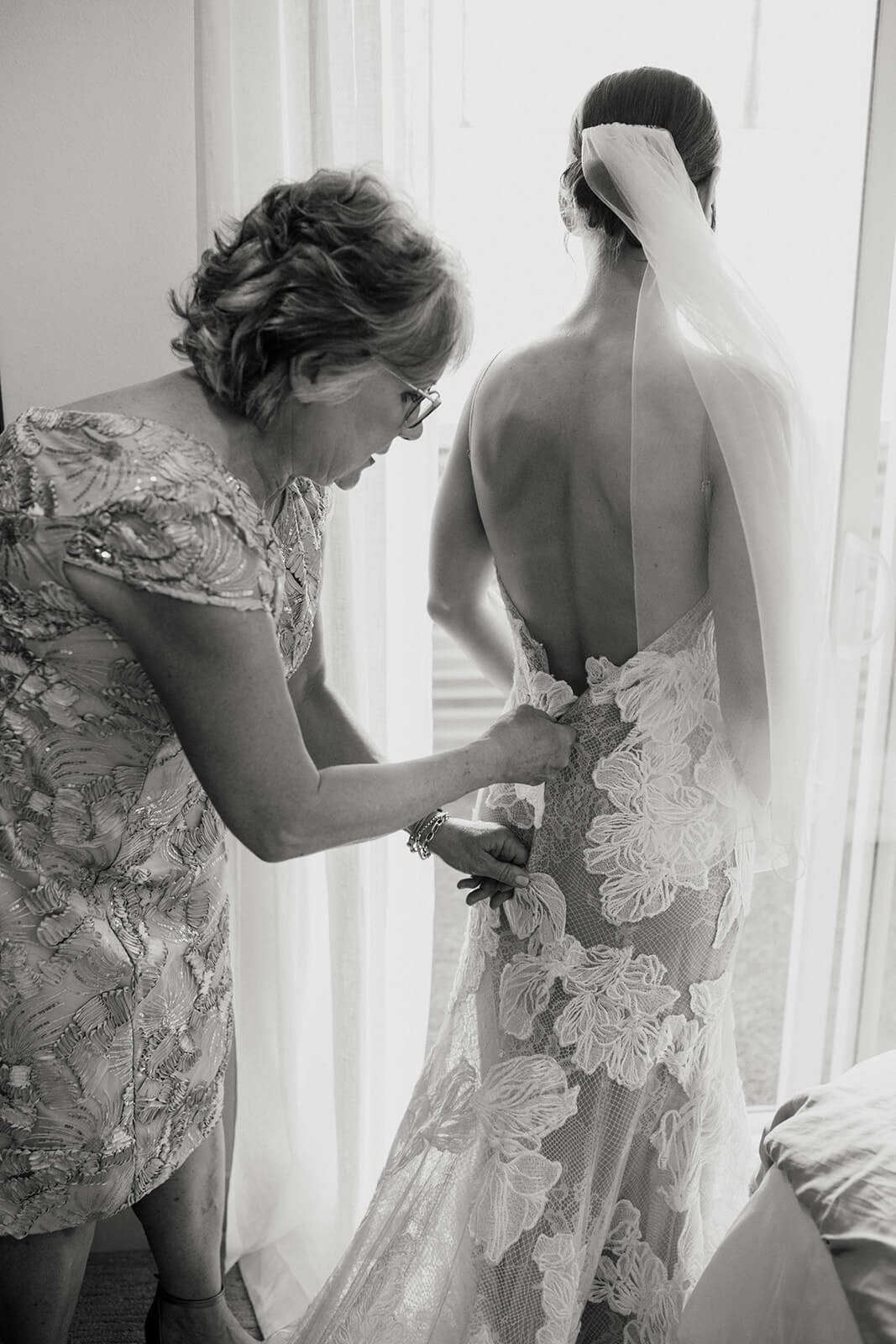 Mother helping bride zip into wedding dress at the Marian Built Loft