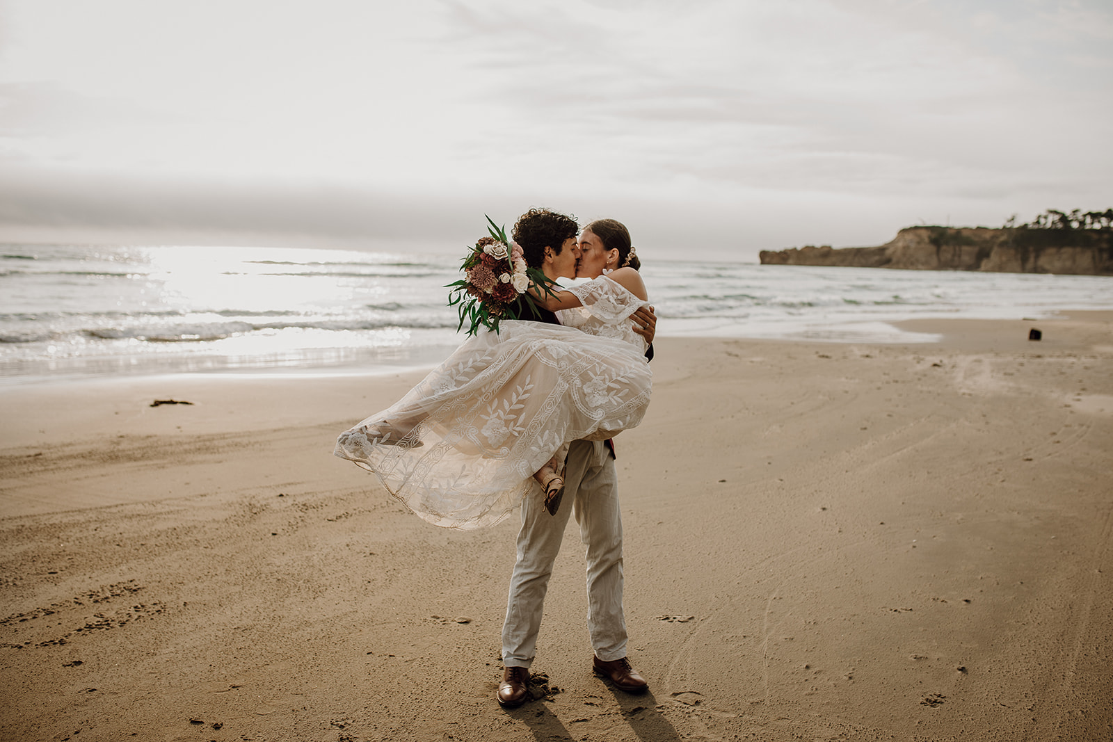 Groom holding bride on the beach at Devil's Punchbowl