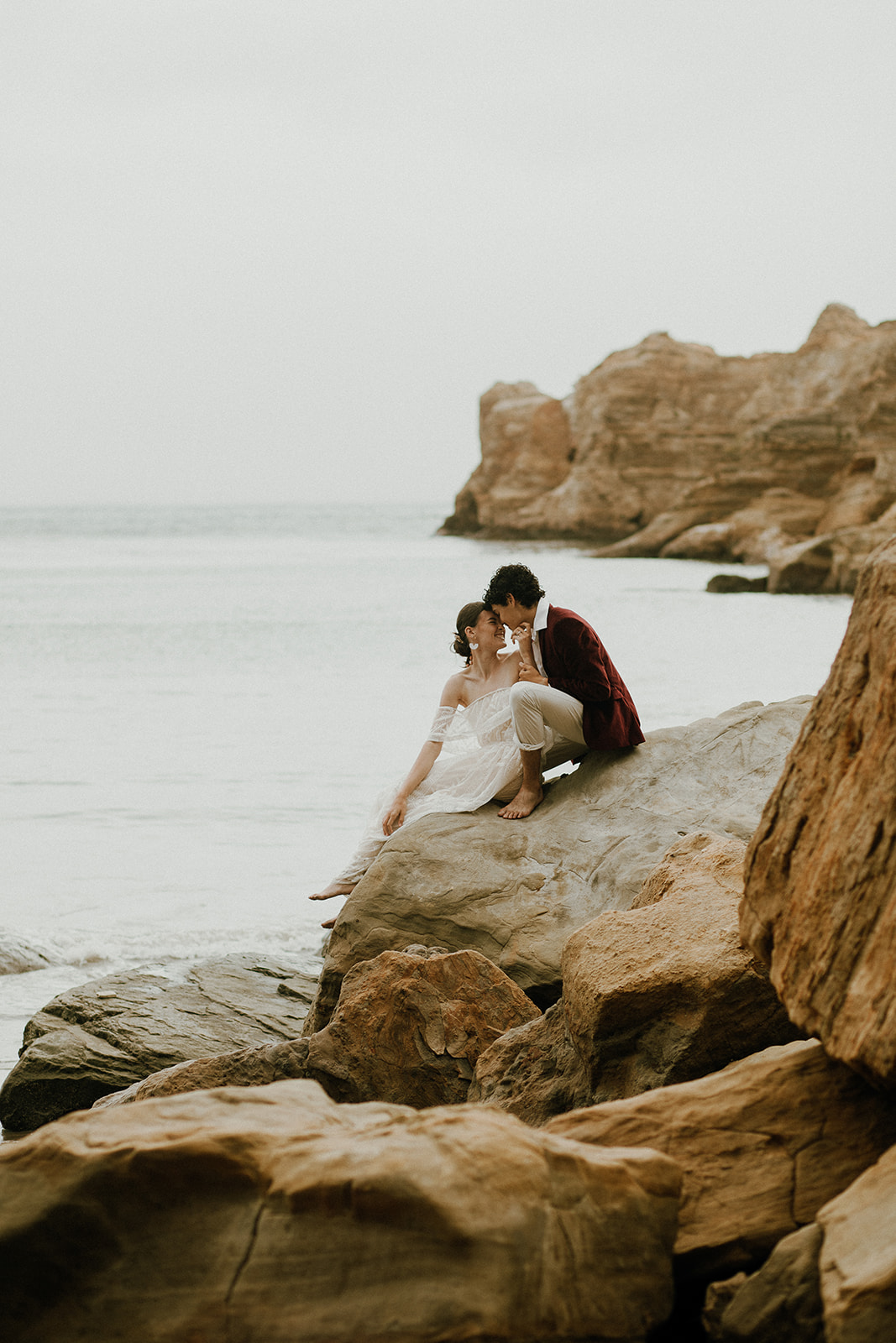 Bride and groom sitting on a rock and kissing at Devil's Punchbowl