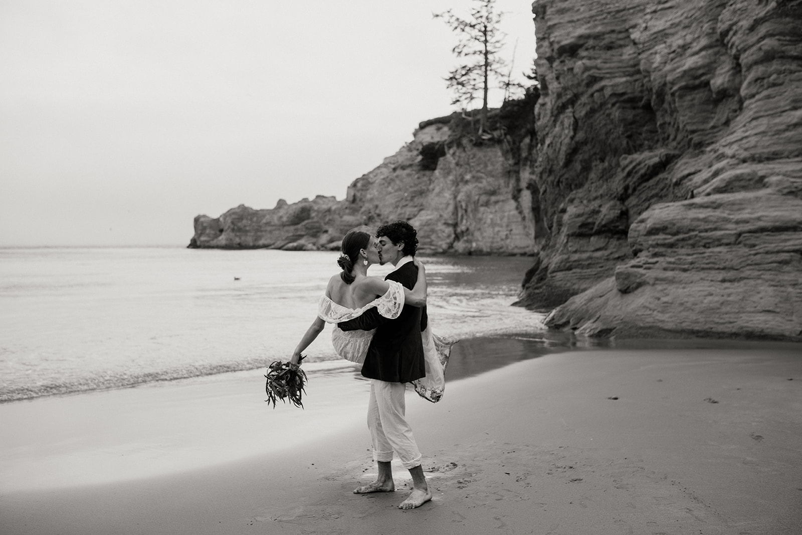 Groom carrying bride and twirling her on the beach for their Oregon Coast elopement