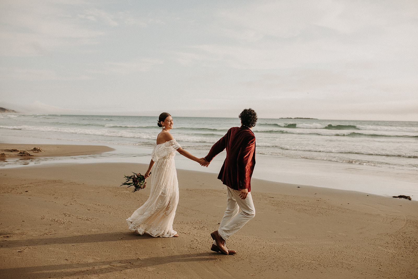 Bride and groom running on the beach at Devil's Punchbowl