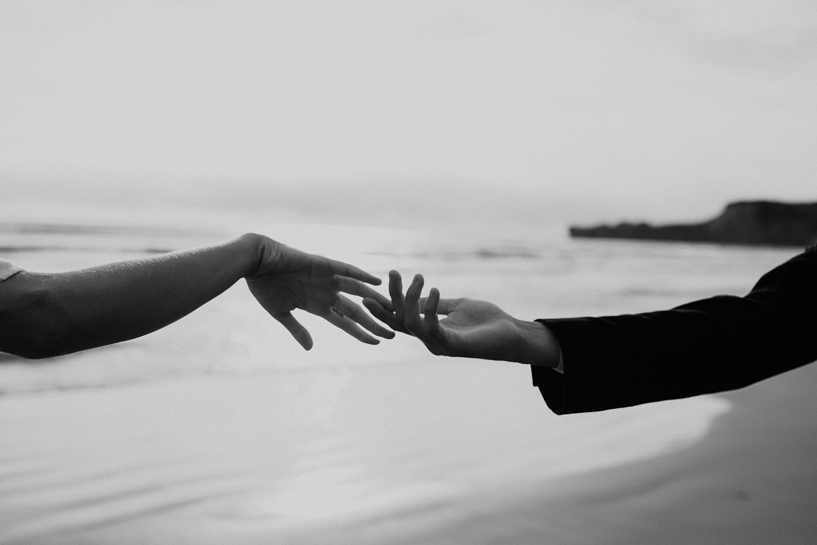 Bride and groom touching hands on the beach at their Oregon Coast elopement