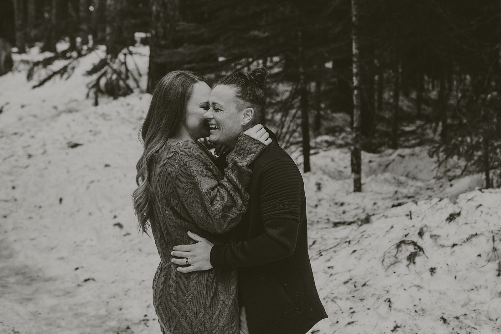 Couple laughing during snowy engagement photo session