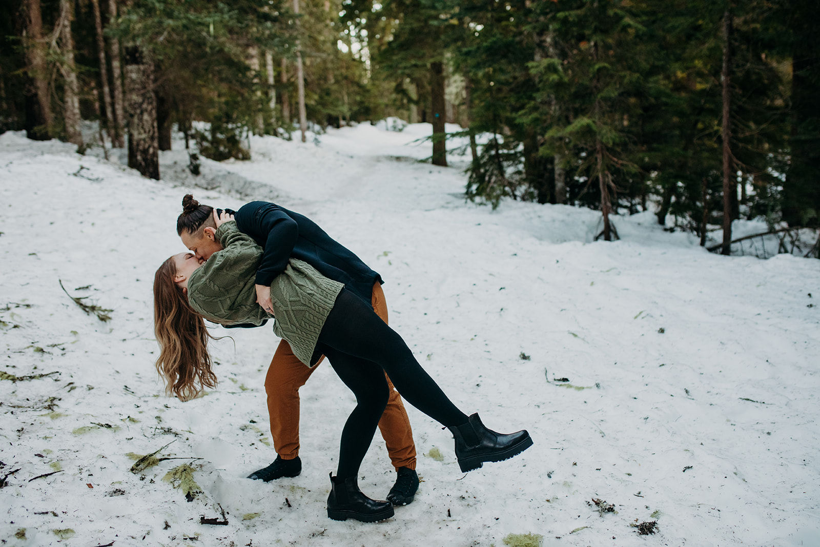 Woman dipping her partner back during snowy engagement session