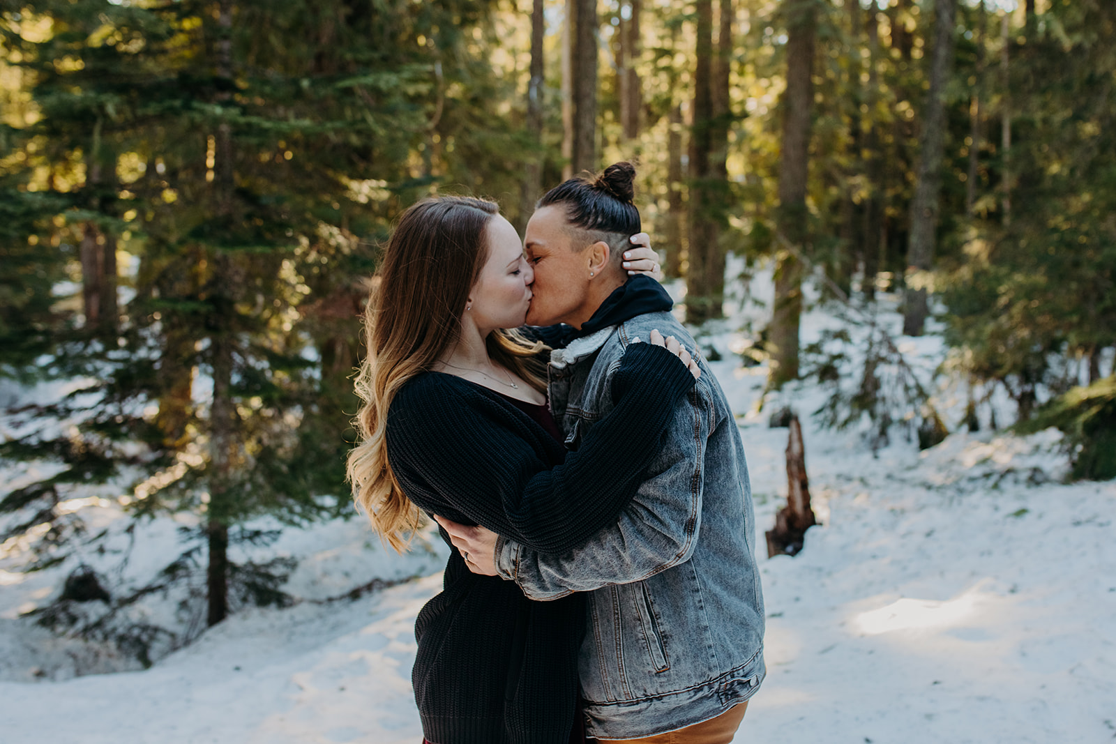 Two women kissing in the snow during engagement photo session