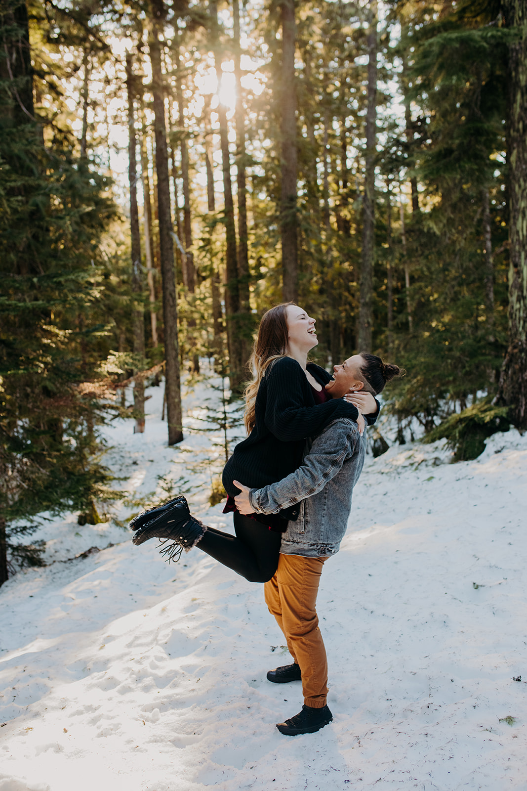 Woman picking her partner up during snowy engagement session
