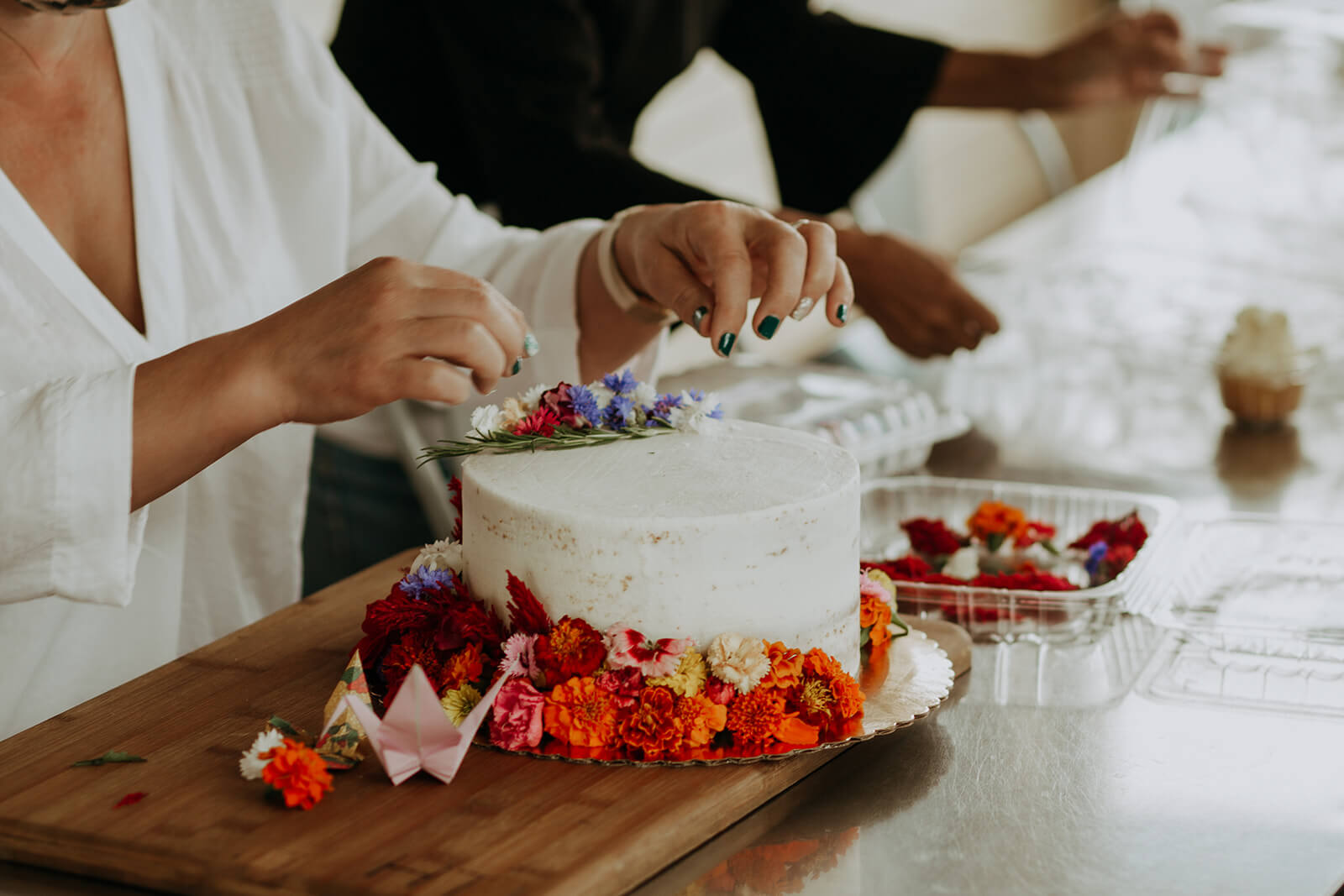 Woman decorating white wedding cake with berries