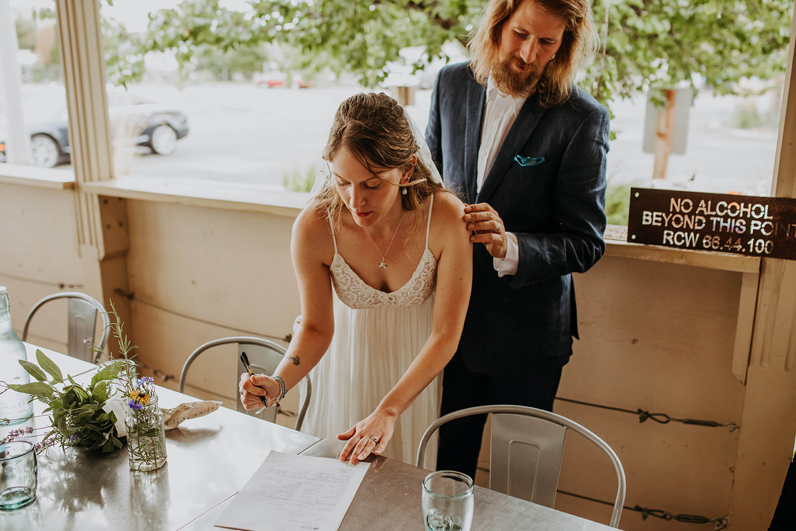 Bride and groom sign marriage license after casual wedding ceremony