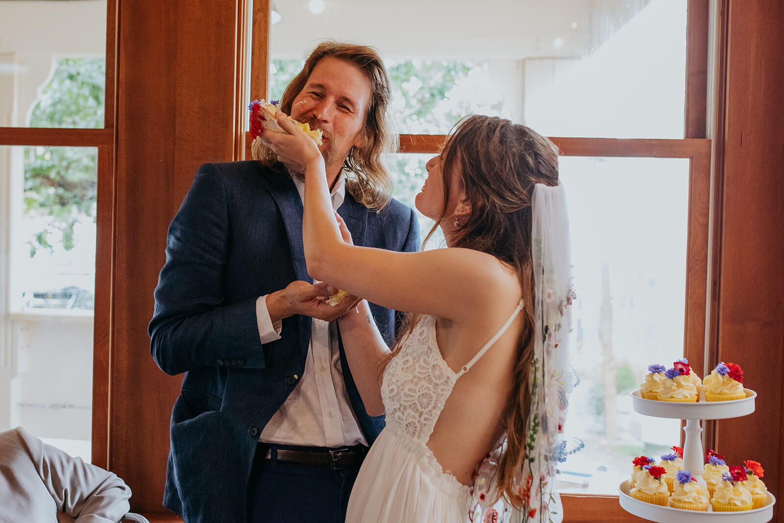 Bride feeds groom cake during casual wedding reception
