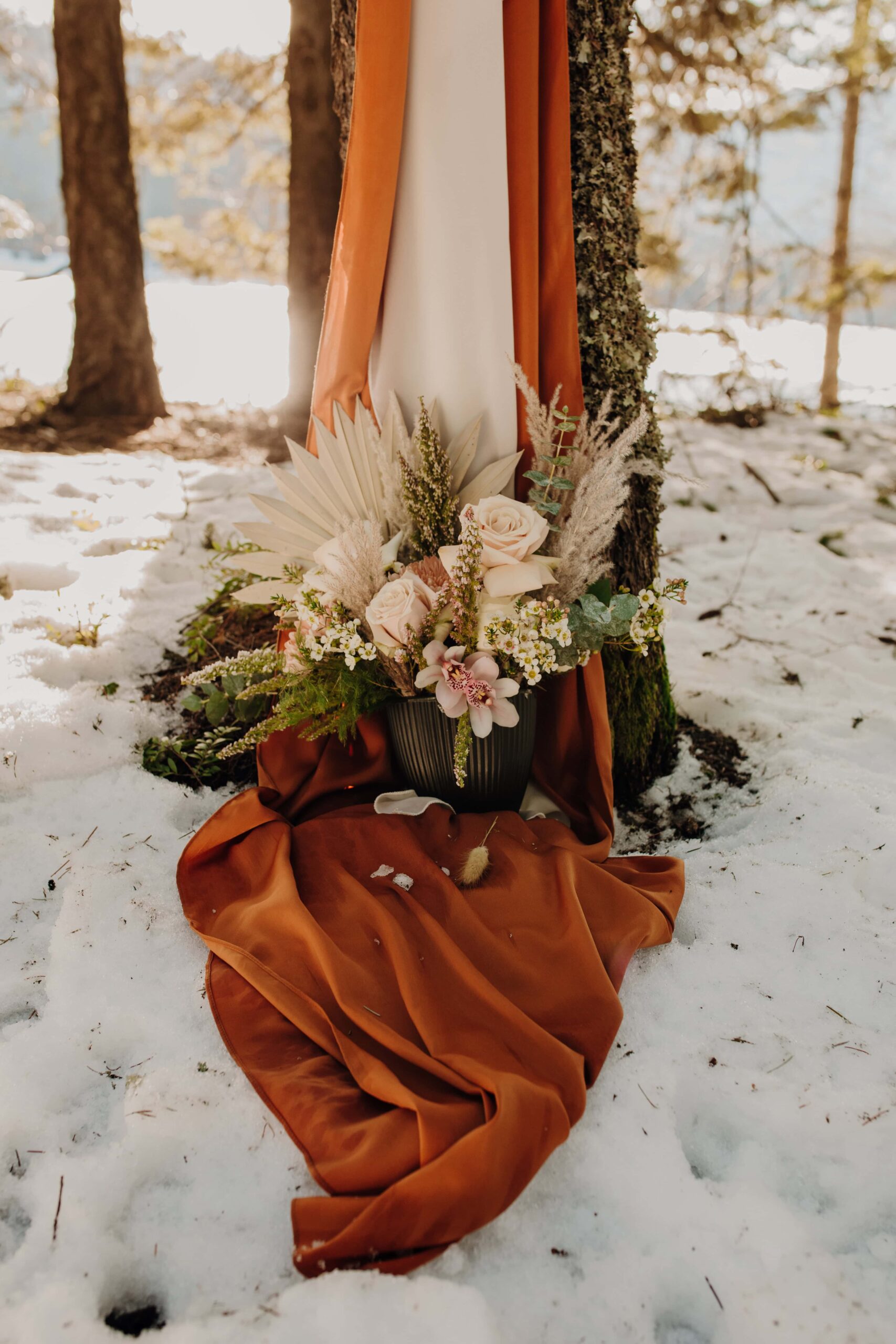 orange drapery sits in this snow with a bouquet of flowers and grasses