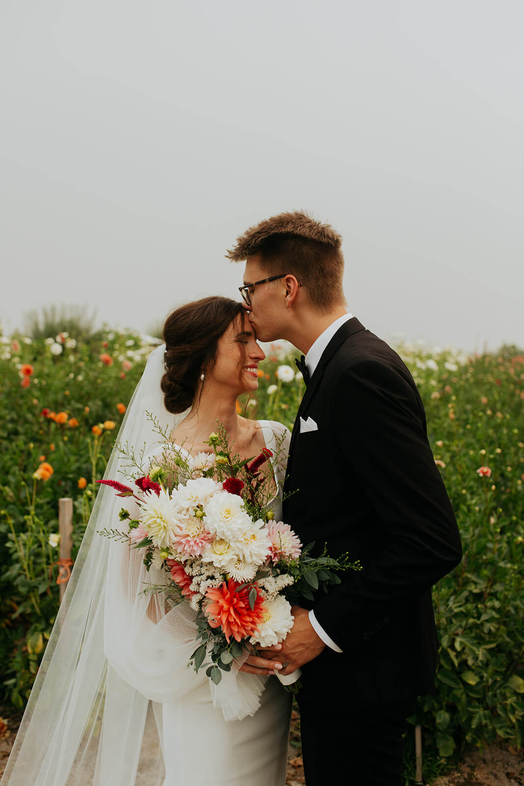 Groom kissing bride on the forehead after first look at family flower farm