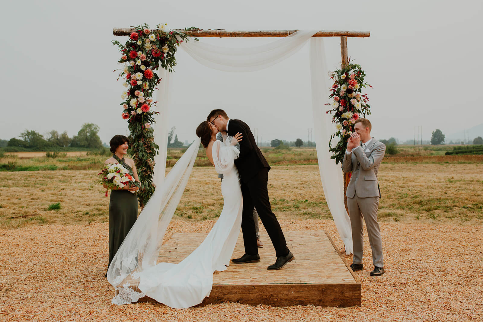 Bride and groom first kiss during outdoor family farm wedding
