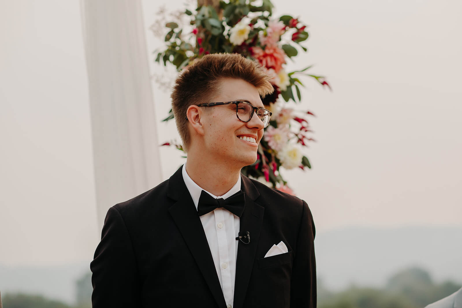 Groom smiling while watching bride walk down the wedding aisle