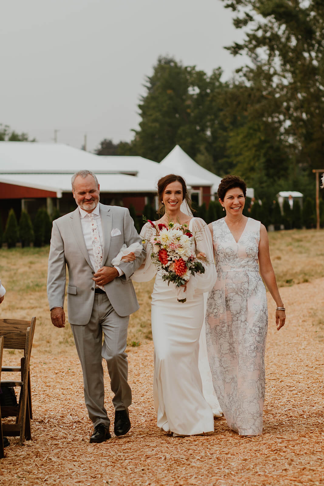 Bride walking with parents down the wedding aisle at Oregon family farm