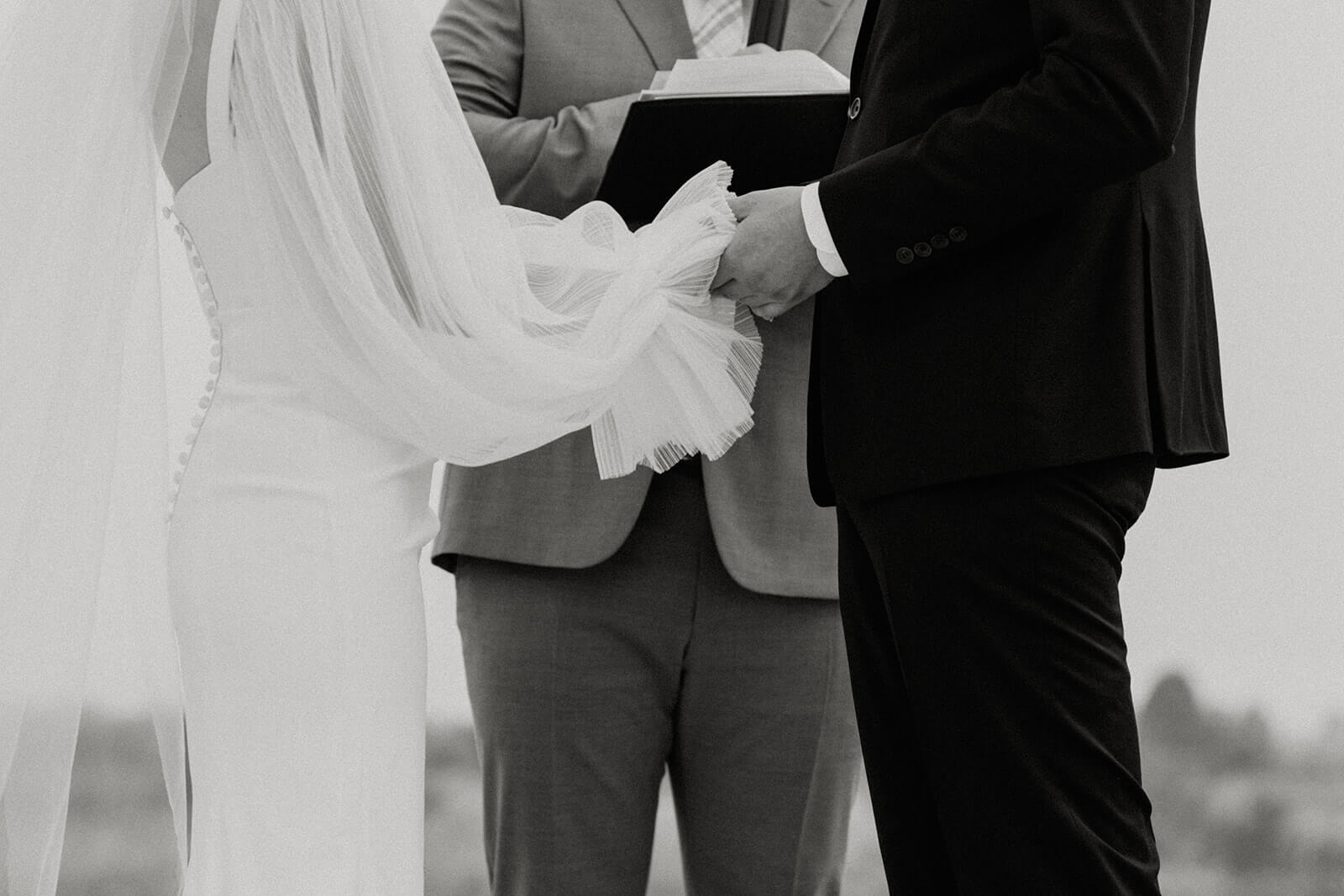 Bride and groom holding hands during outdoor wedding ceremony