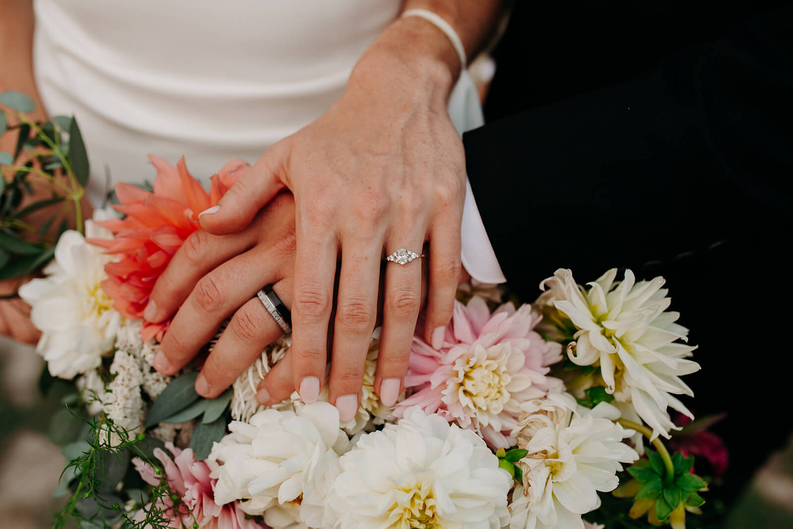 Bride and groom rings resting on top of DIY wedding flowers
