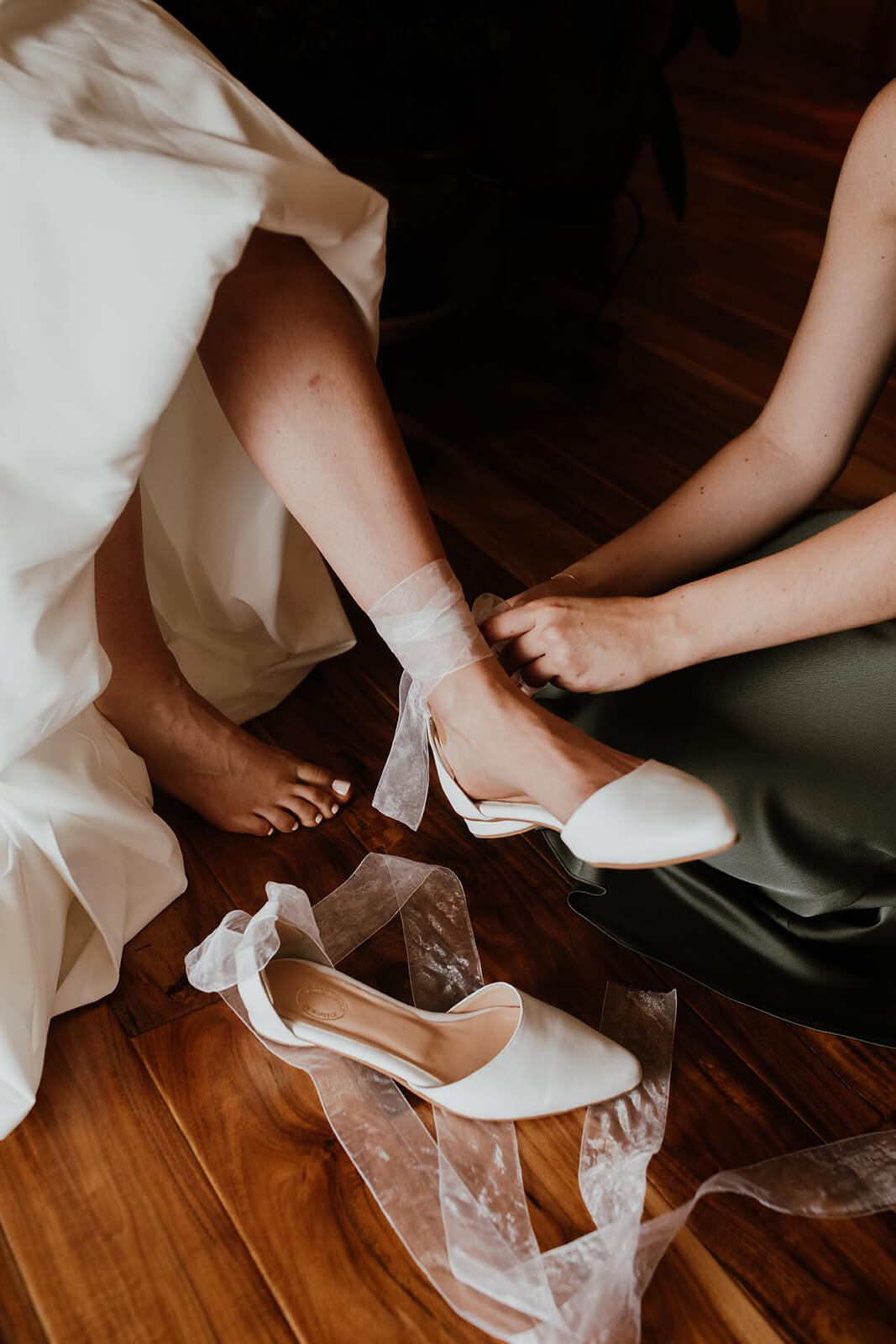 Bride putting on white flats with tulle ribbon