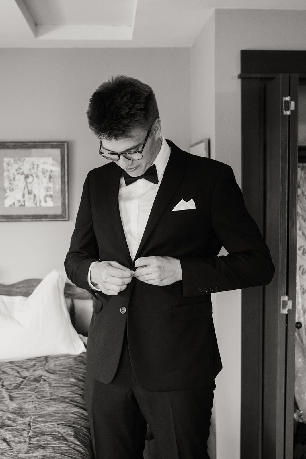 Groom buttoning black suit for Oregon family farm wedding