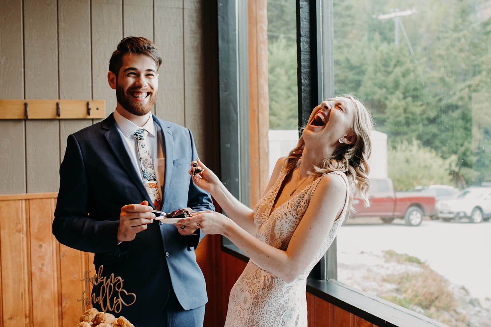 Bride and groom laugh during cake cutting at ski wedding