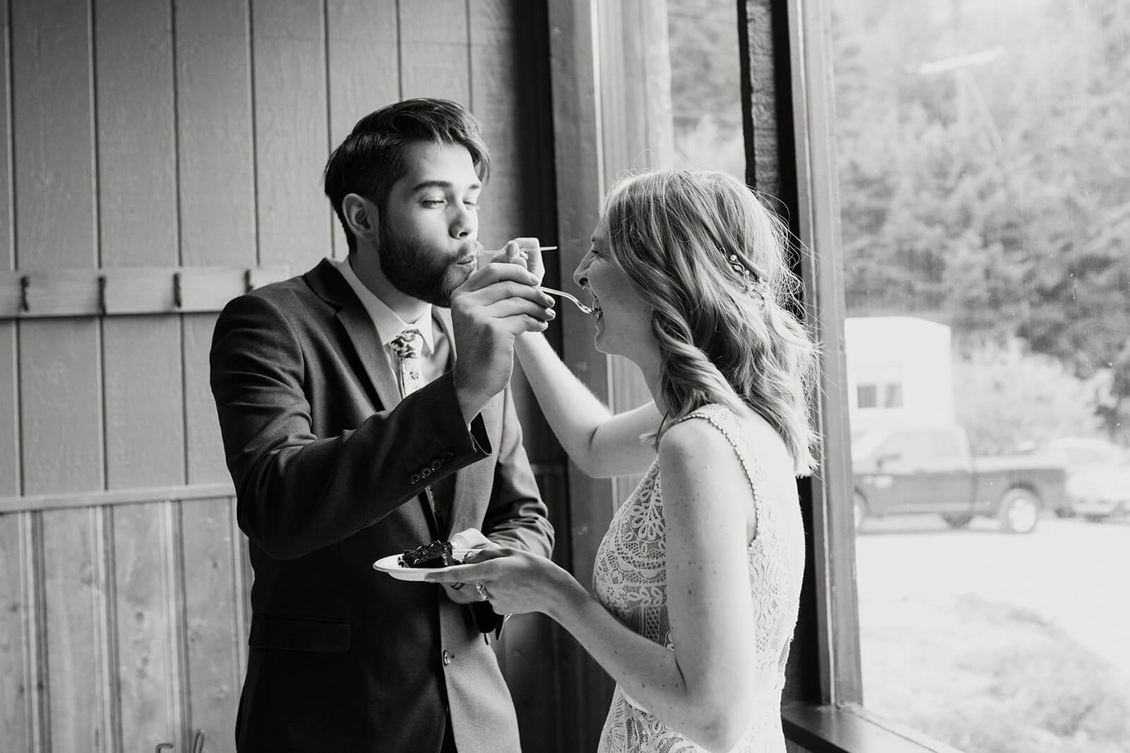 Bride and groom feed each other cake at ski wedding