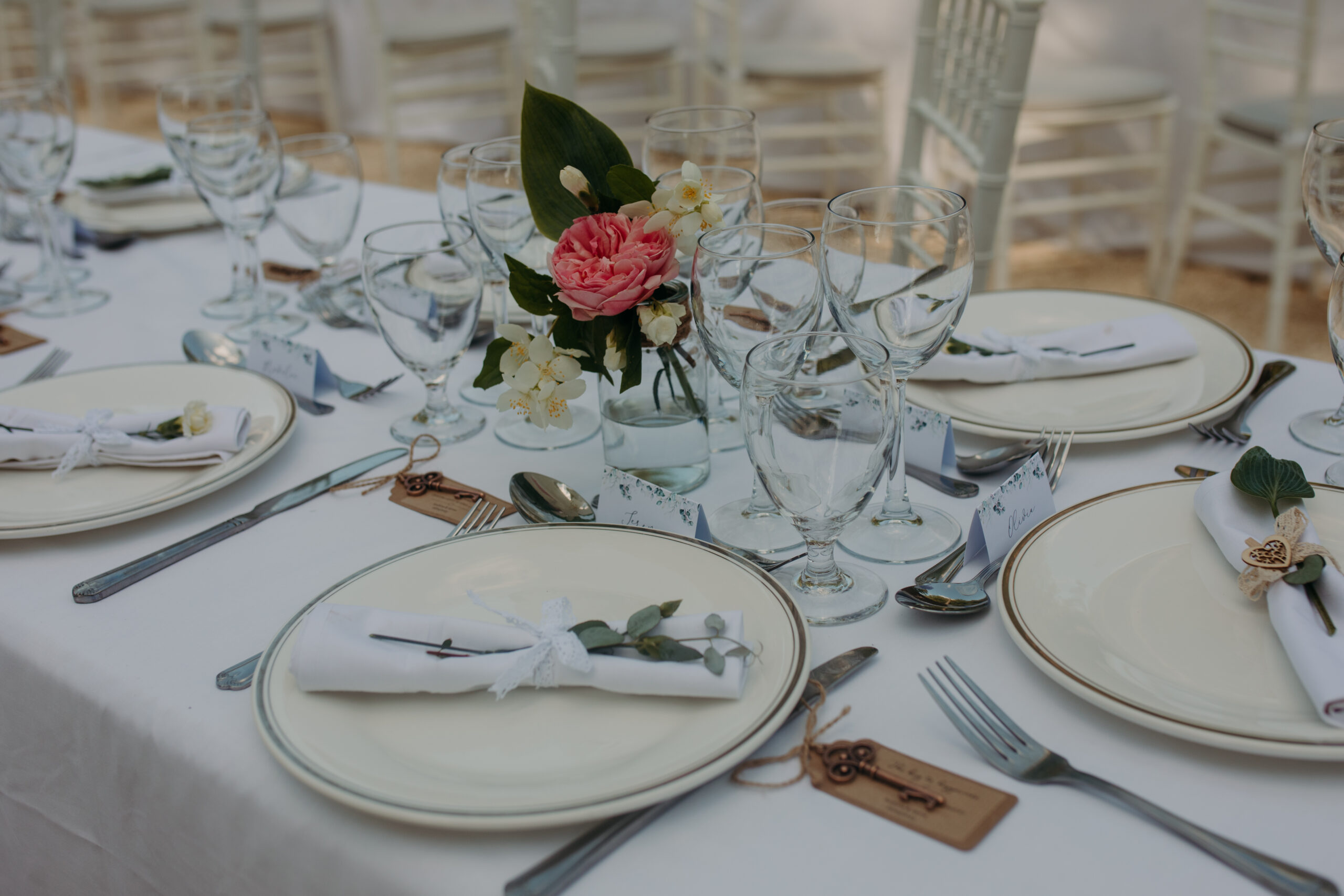 Plates and cutlery are laid out on table with rose centerpiece