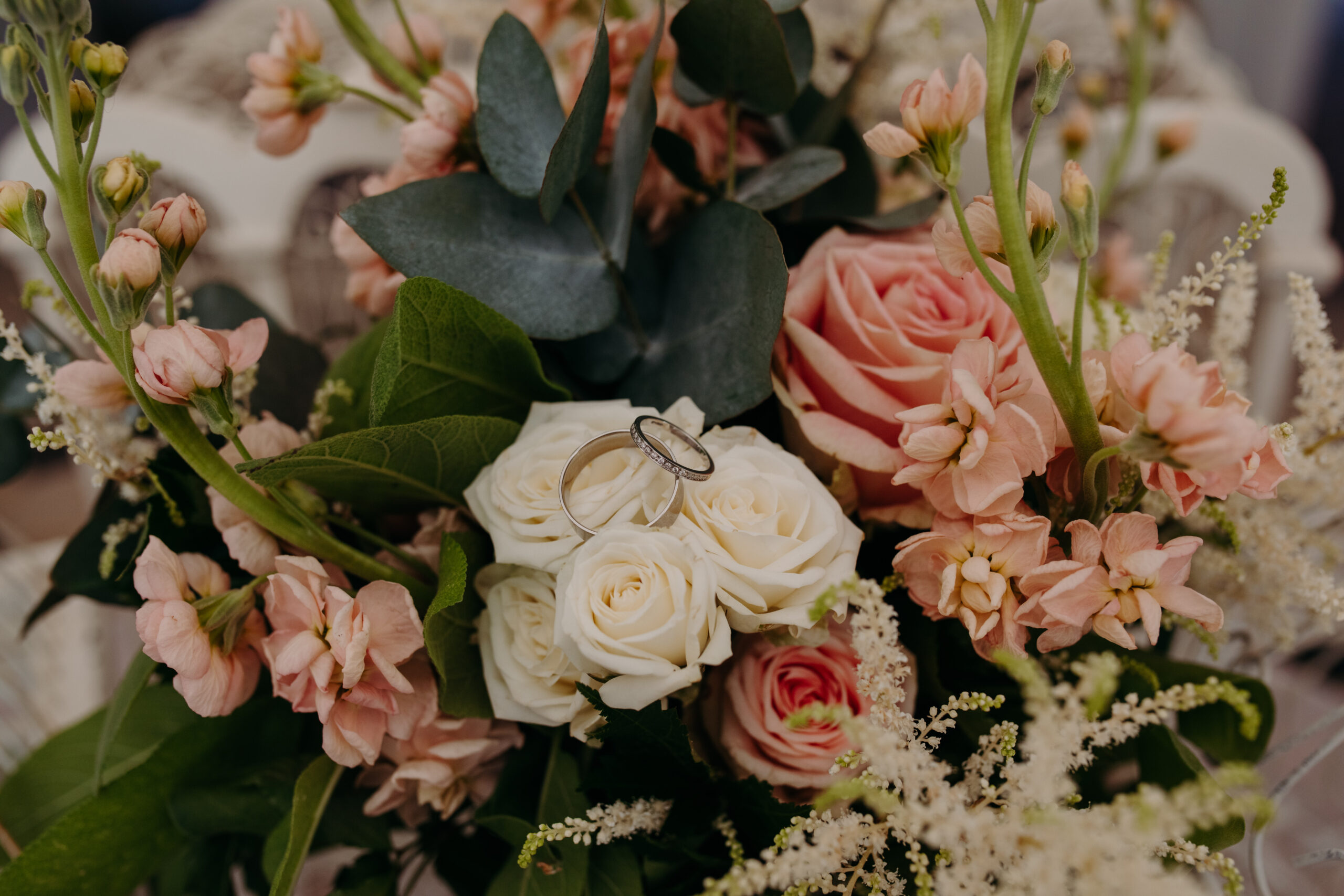 Two rings sit nestled atop one another on a bouquet of roses. 