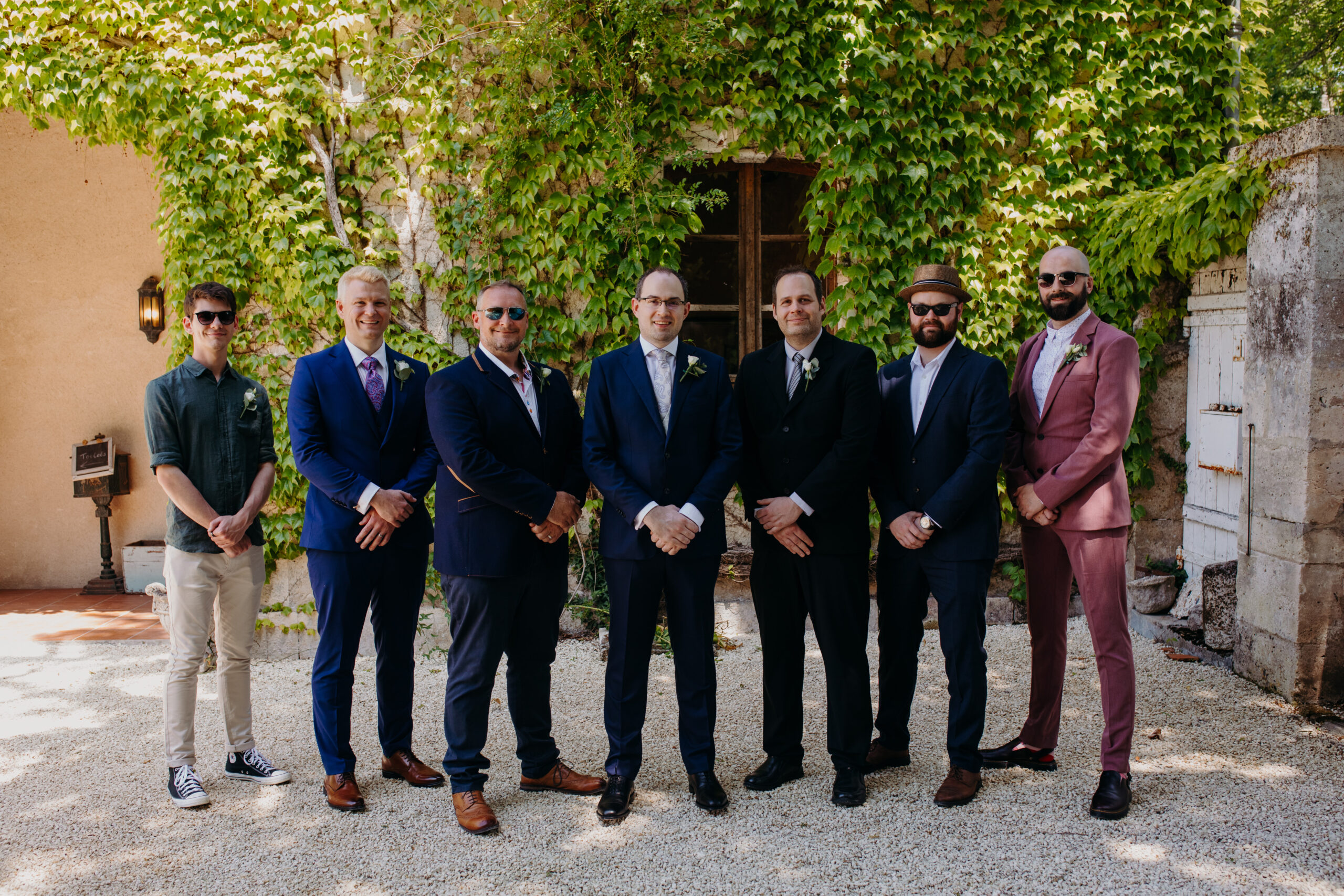 men gather around groom outside in front of ivy covered chateau