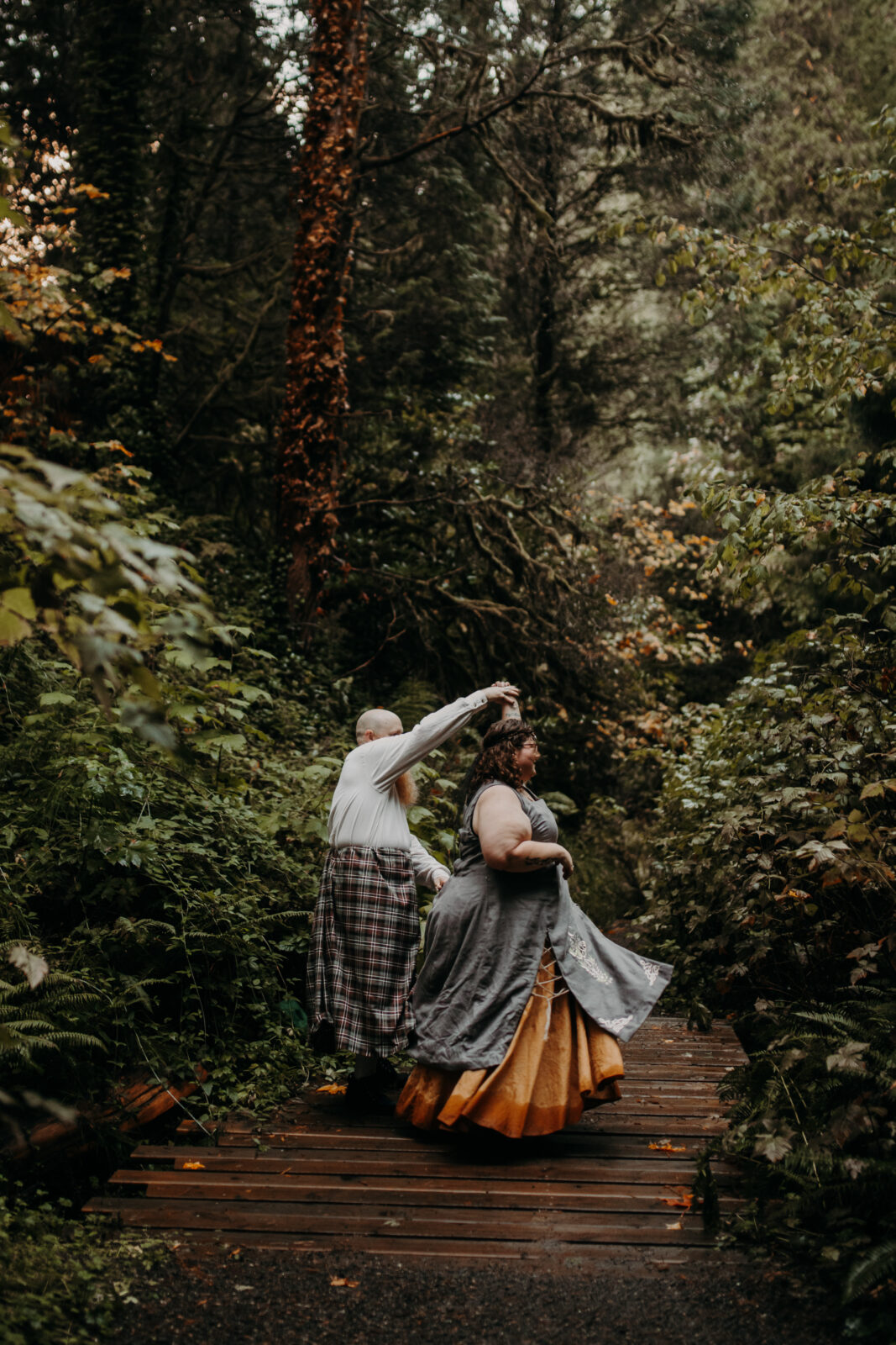 man twirls woman in forest at Hoyt Arboretum