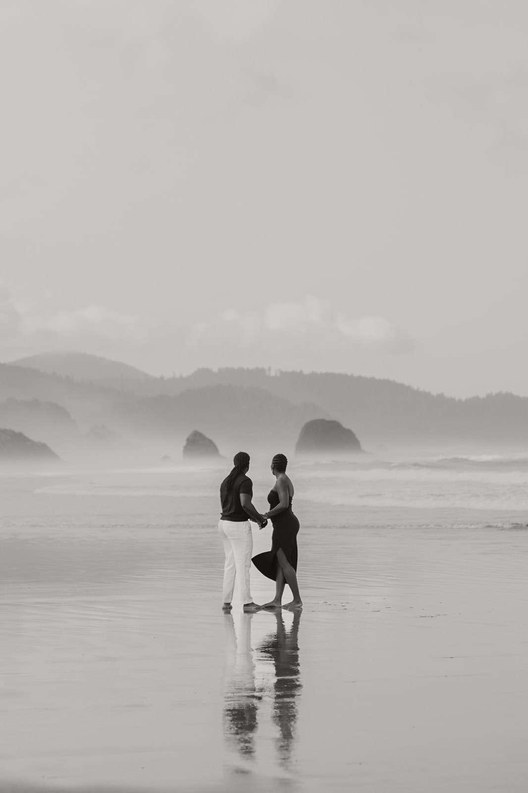 black and white photo of a couple on the beach at Haystack Rock in Cannon Beach 