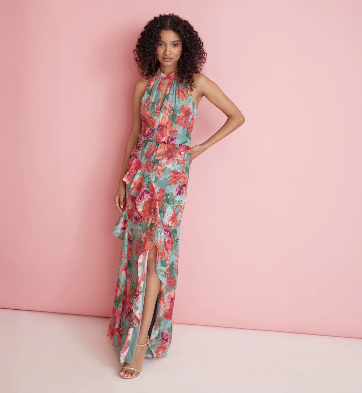 woman stands in festive dress in a turquoise dress with pink flowers