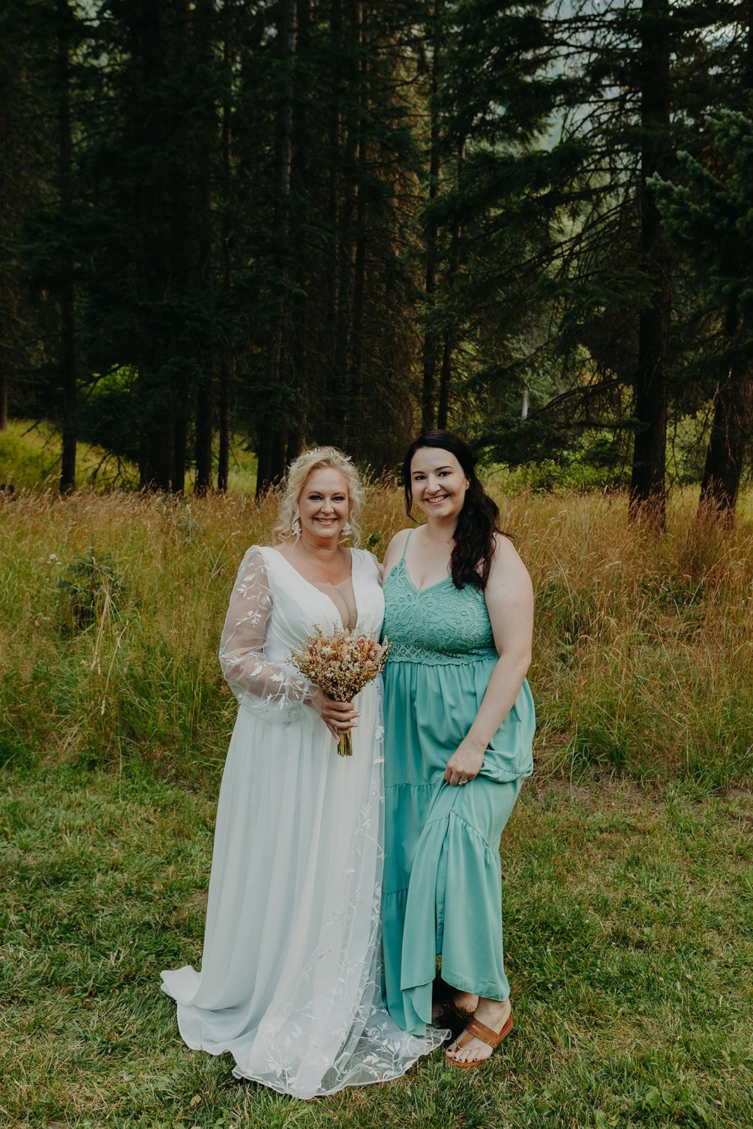 older bride stands next to a younger woman smiling wearing beach wedding dress code attire