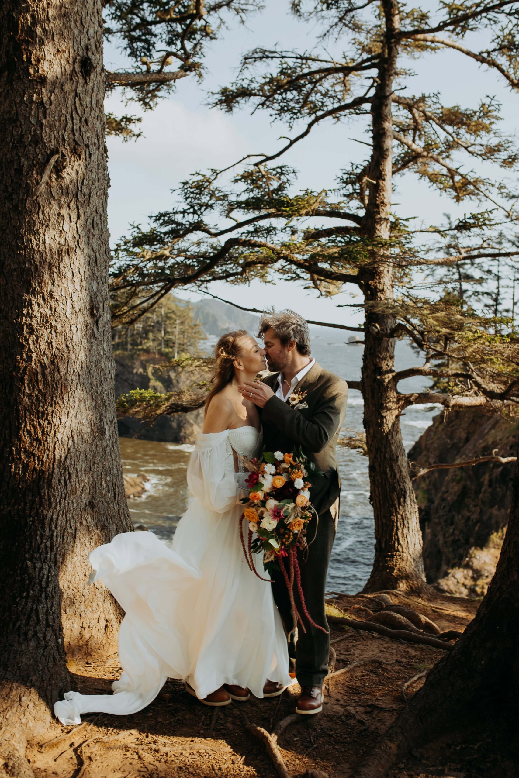 A man and woman kiss on a windswept cliff at the Samuel H. Boardman scenic corridor scenic bridges. 