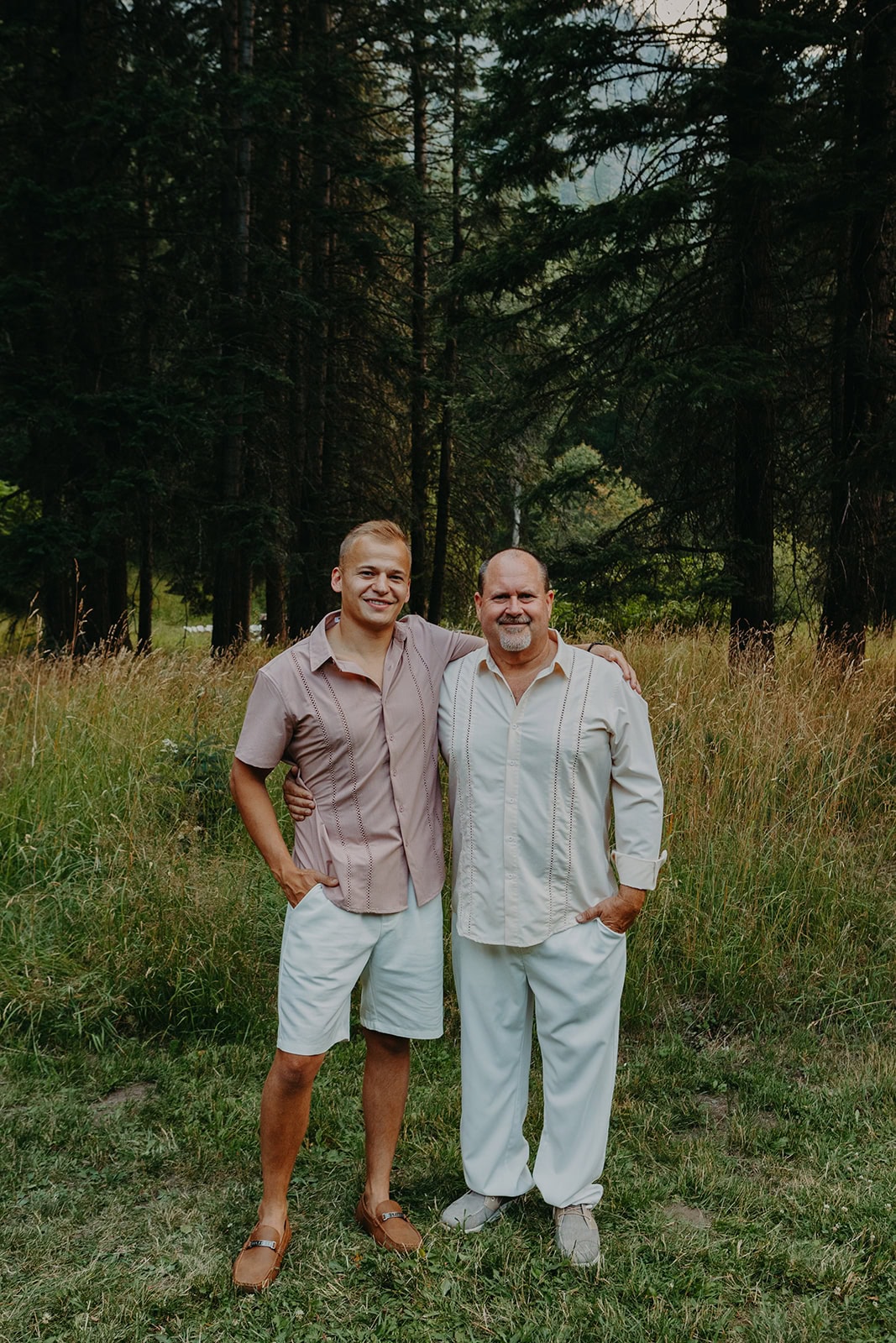 older groom stands next to a younger man smiling wearing beach wedding dress code attire