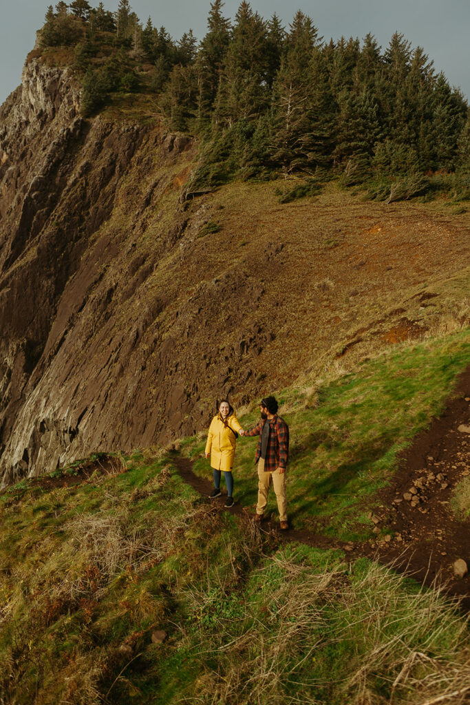 a couple walk hand in hand on the cliff at the Elk Flats trail overlooking the ocean 