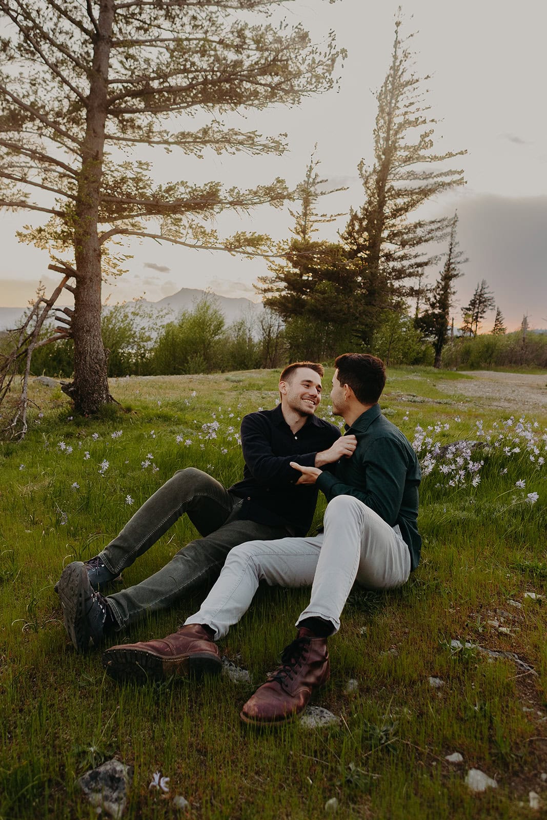 two men sit on a patch of grass exchanging loving looks at the Columbia River Gorge