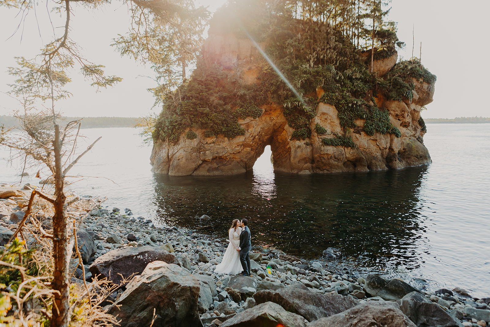 a couple at Rockaway Beach stand in front of a scenic arch rock rising out of the ocean