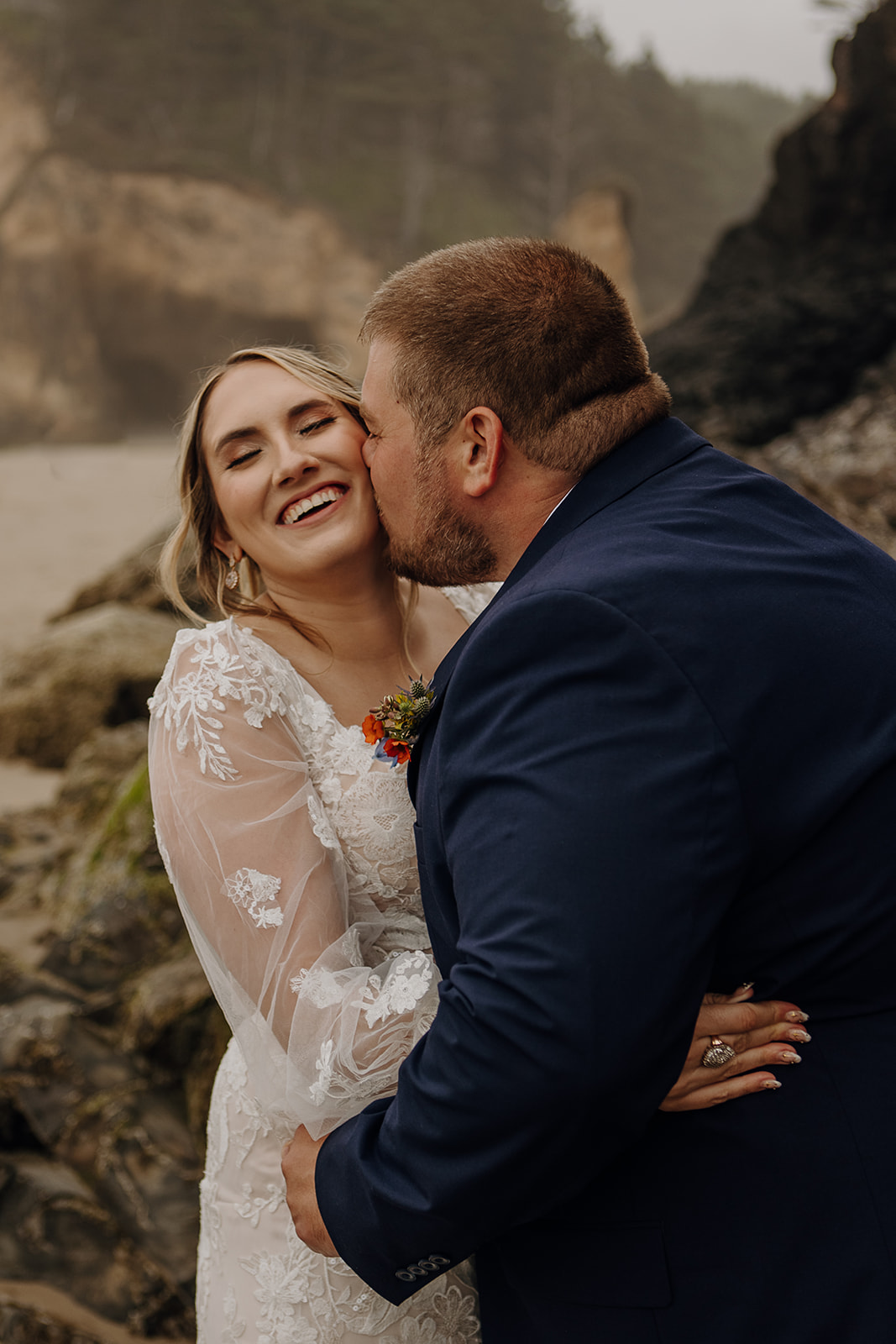 a groom kisses his ecstatic bride on the beach at Hug Point State Recreation Site on the Oregon Coast