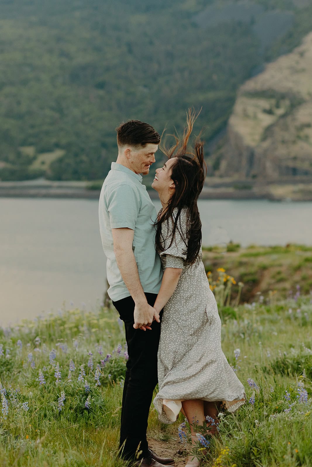 man and woman stand in a field amidst flowers smiling at each other