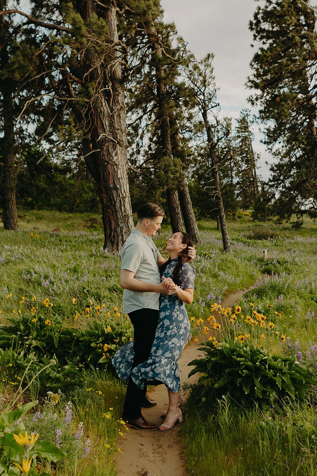 man and woman stand in a field amidst flowers smiling at each other