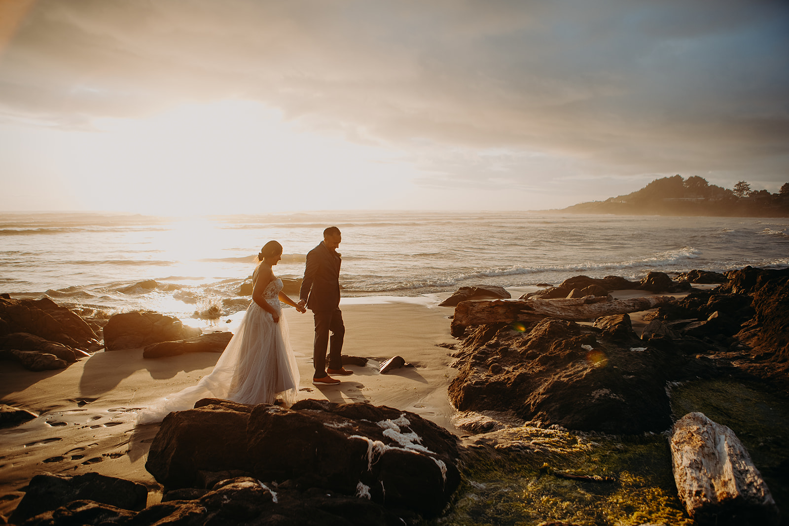 a bride and groom walk along the shores hand in hand in Yachats for this Oregon Coast elopement