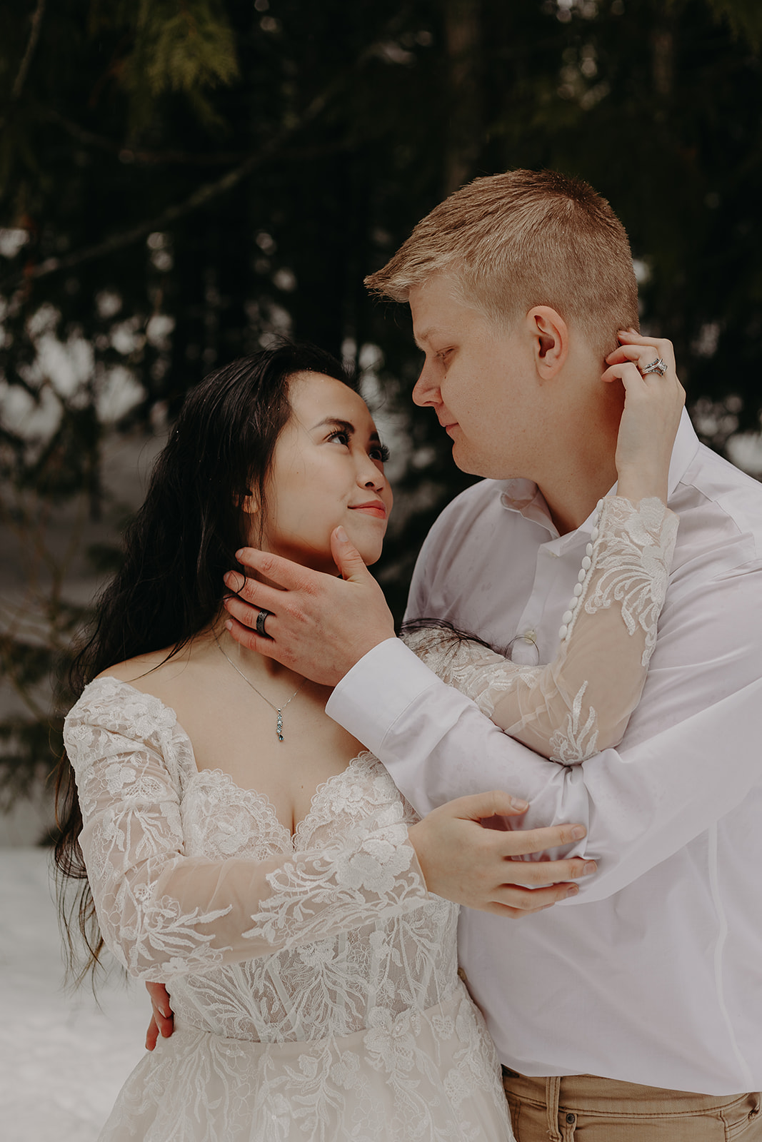 man and woman embrace and look at each other as snow falls at Mount Hood